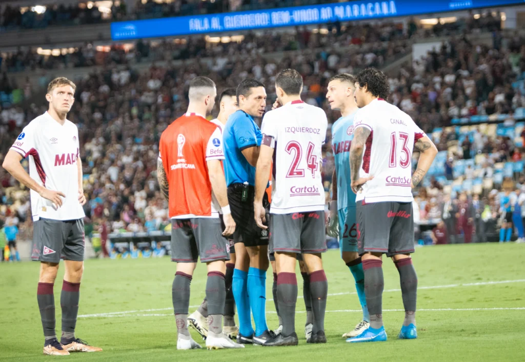 Jugadores de Lanús con árbitro Jesús Valenzuela